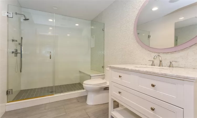 Bathroom with an enclosed shower, vanity, and toilet