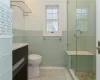 Bathroom with vanity, tile patterned floors, toilet, tile walls, and a shower with shower door