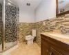 Bathroom with walk in shower, vanity, tile walls, tile patterned flooring, and toilet