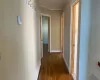 Hallway featuring wood-type flooring, a baseboard radiator, and ornamental molding