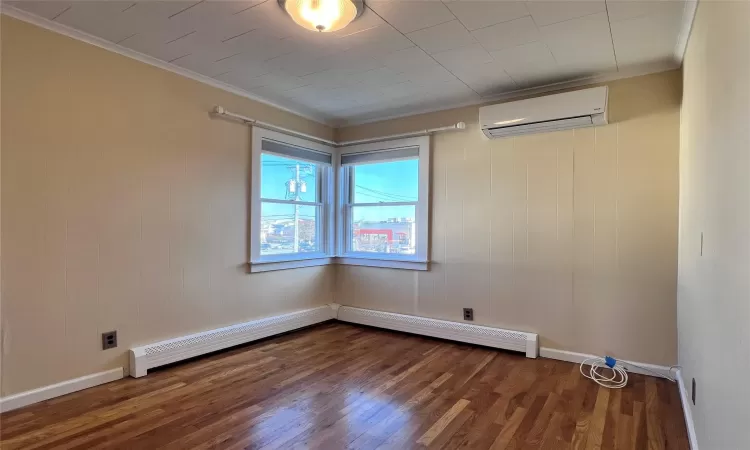 Bedroom 2 featuring an AC wall unit, dark hardwood / wood-style flooring, a baseboard heating unit, and ornamental molding