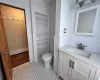 Bathroom with built in shelves, vanity, toilet, and baseboard heating