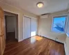 Bedroom 1 featuring an AC wall unit, crown molding, a closet, and dark wood-type flooring