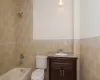 Full bathroom with vanity, tiled shower / bath combo, tile walls, and toilet