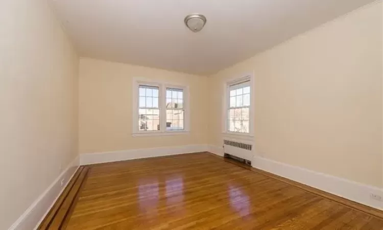 Empty room featuring radiator and wood-type flooring