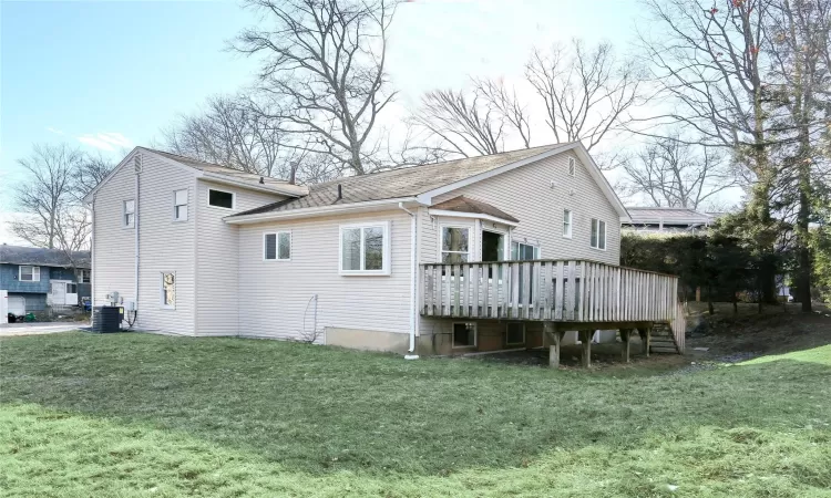 Back of house with a lawn, central air condition unit, and a wooden deck