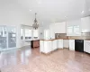 Kitchen with white cabinetry, an inviting chandelier, black dishwasher, backsplash, and pendant lighting