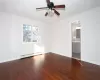 Empty room featuring hardwood / wood-style flooring, ceiling fan, and a baseboard radiator