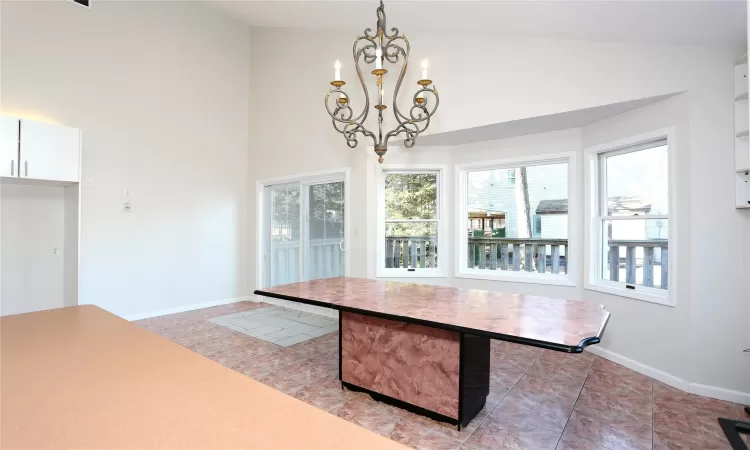 Dining room with tile patterned flooring, high vaulted ceiling, and an inviting chandelier