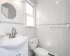 Bathroom featuring toilet, vanity, tile walls, and a baseboard heating unit