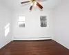 Unfurnished room with ceiling fan, dark hardwood / wood-style flooring, and a baseboard heating unit