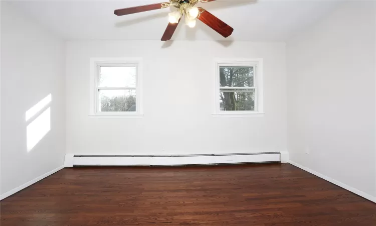 Unfurnished room with ceiling fan, dark hardwood / wood-style flooring, and a baseboard heating unit