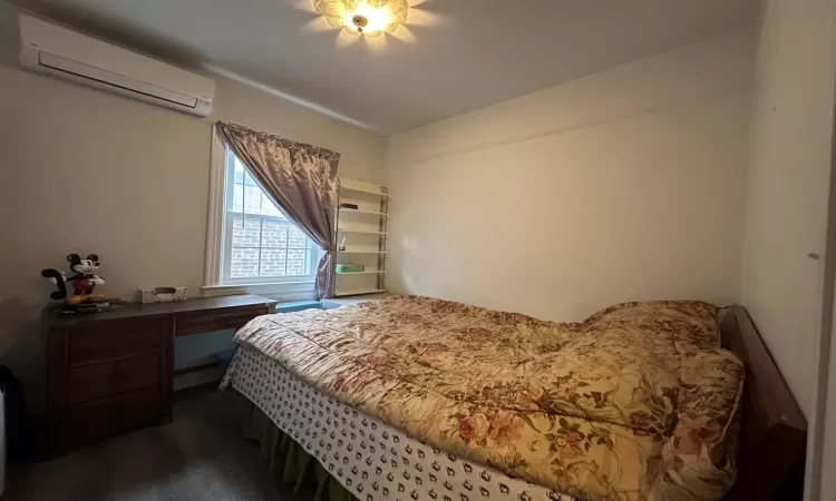 Bedroom featuring dark hardwood / wood-style floors and an AC wall unit