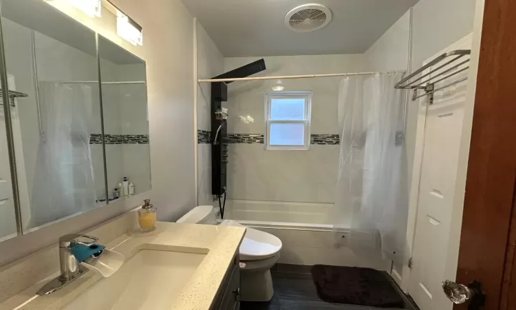 Full bathroom featuring toilet, vanity, and shower / tub combo with curtain