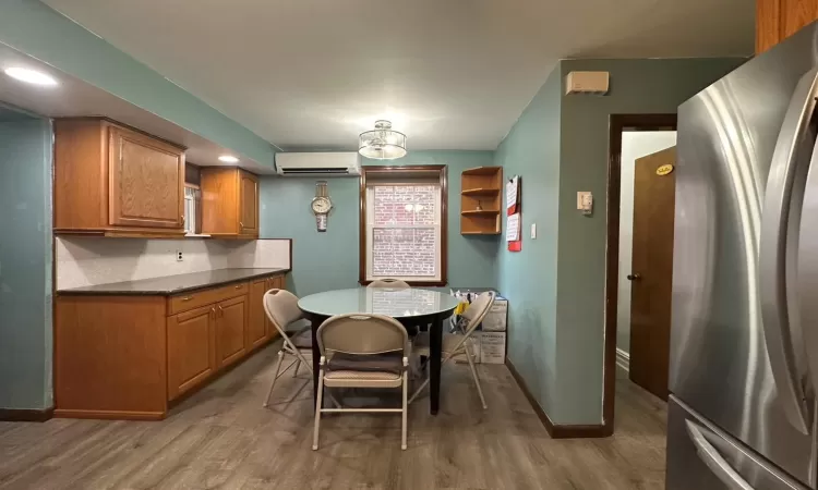 Kitchen with hardwood / wood-style floors, tasteful backsplash, stainless steel refrigerator, and a wall mounted AC