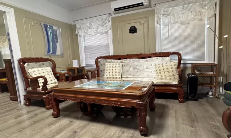 Living area featuring a wall mounted AC and wood-type flooring