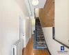 Stairs with hardwood / wood-style floors, radiator, and brick wall