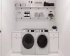 Laundry area with washing machine and clothes dryer, light tile patterned flooring, and cabinets