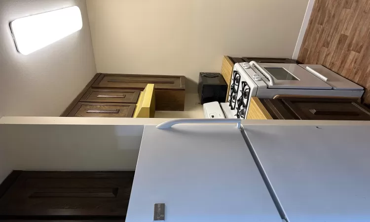 Kitchen with refrigerator, dark brown cabinets, exhaust hood, range, and butcher block countertops