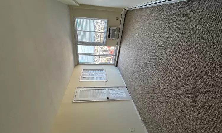 Unfurnished room with an AC wall unit, dark carpet, and a baseboard heating unit