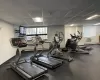 Workout area featuring an AC wall unit, a drop ceiling, and a baseboard heating unit