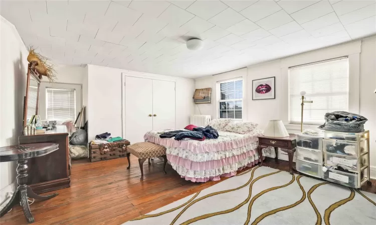 Bedroom with radiator heating unit and hardwood / wood-style flooring