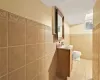 Bathroom featuring tile patterned flooring, vanity, toilet, and tile walls