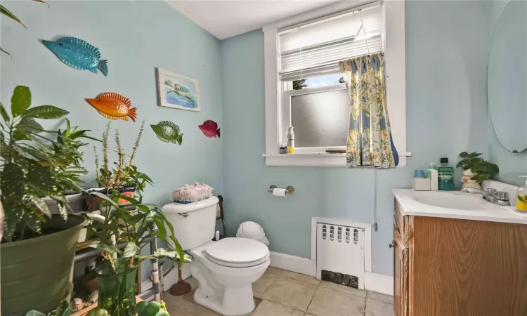 Bathroom with tile patterned flooring, vanity, toilet, and radiator heating unit