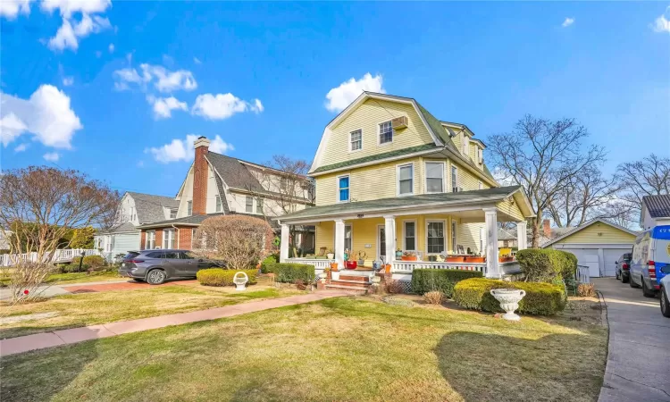 View of front of house with a porch, a front lawn, an outdoor structure, and a garage