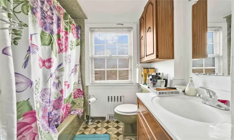 Full bathroom with vanity, toilet, shower / bathtub combination with curtain, and radiator