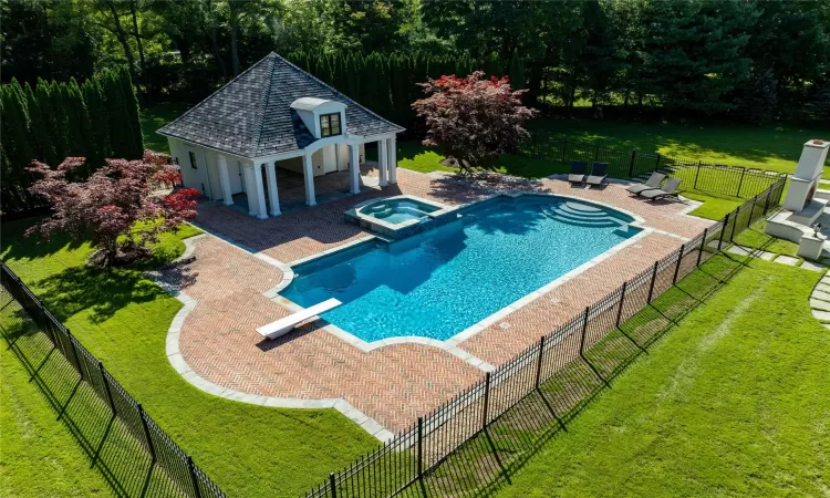 View of pool with an in ground hot tub, a yard, a diving board, and a patio area