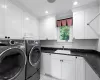 Clothes washing area with cabinets, separate washer and dryer, ornamental molding, and sink