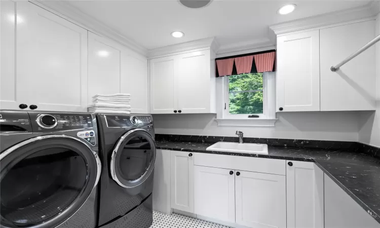 Clothes washing area with cabinets, separate washer and dryer, ornamental molding, and sink