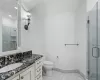 Bathroom with vanity, toilet, and a shower with door