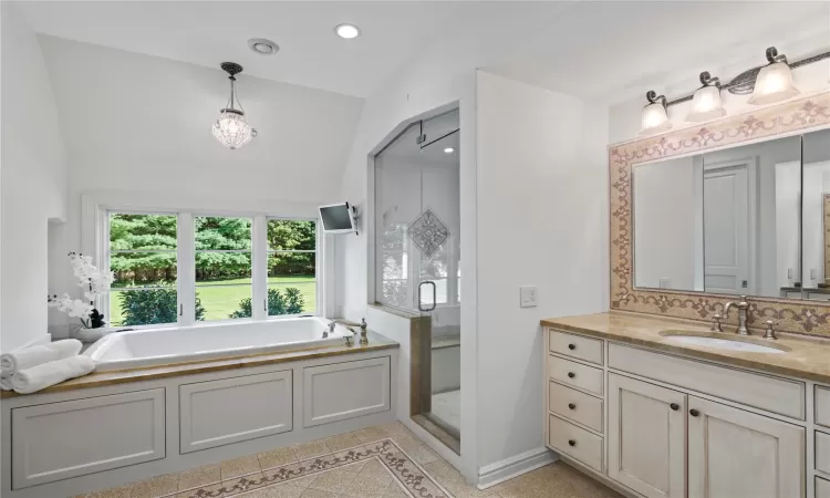 Bathroom featuring tasteful backsplash, tile patterned flooring, lofted ceiling, vanity, and independent shower and bath