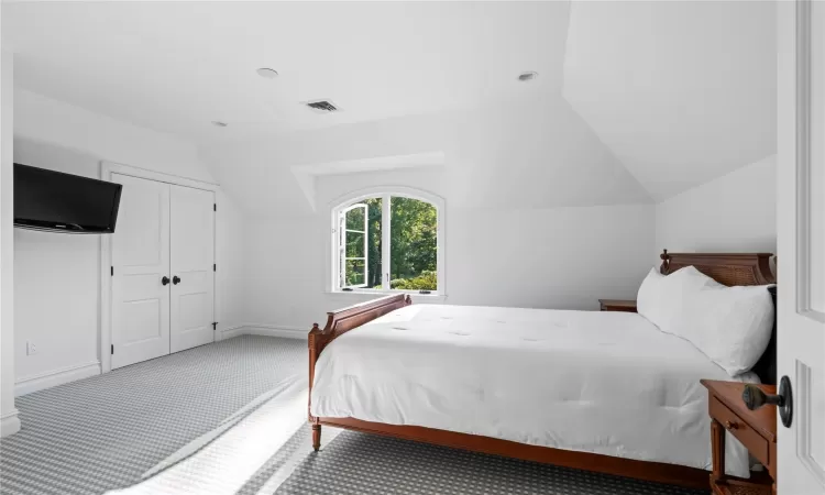 Carpeted bedroom with a closet and lofted ceiling