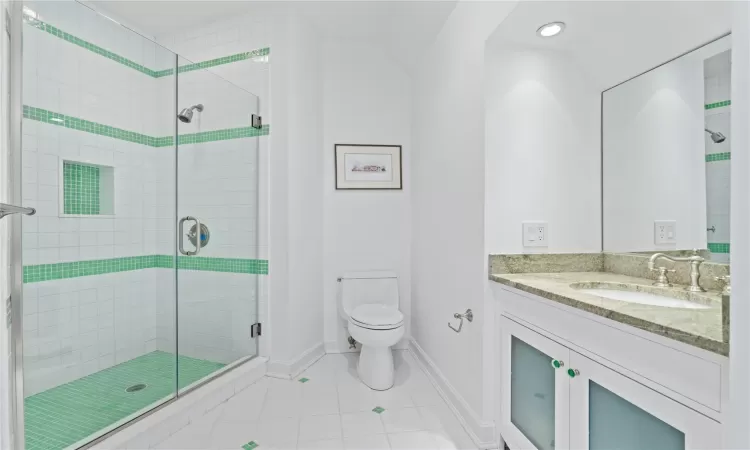 Bathroom featuring tile patterned flooring, vanity, toilet, and a shower with shower door