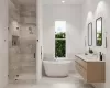 Bathroom featuring vanity, plenty of natural light, tile walls, and independent shower and bath