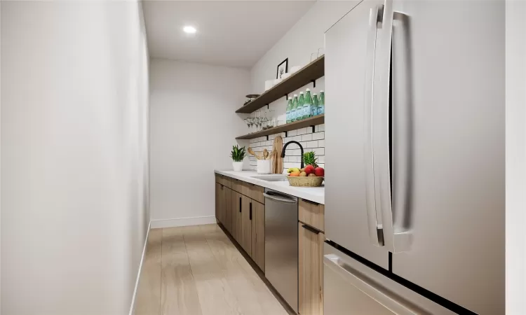 Bar with decorative backsplash, appliances with stainless steel finishes, light wood-type flooring, and sink