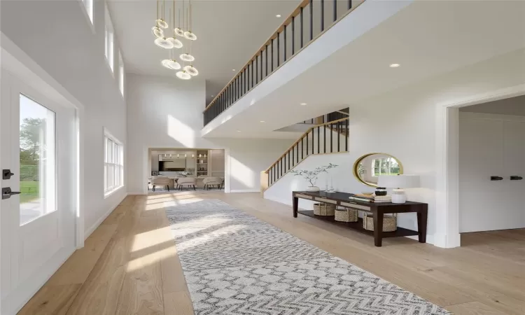 Entryway featuring an inviting chandelier, a high ceiling, and light wood-type flooring