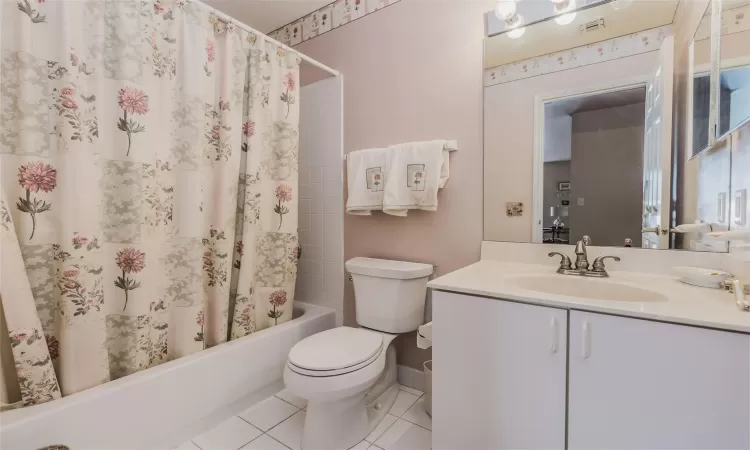 Full bathroom with tile patterned flooring, vanity, toilet, and shower / bathtub combination with curtain