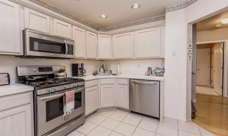 Kitchen featuring sink, light tile patterned floors, and stainless steel appliances