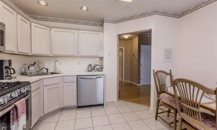 Kitchen featuring light tile patterned flooring, sink, and appliances with stainless steel finishes