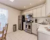 Kitchen with sink, light tile patterned floors, ornamental molding, and appliances with stainless steel finishes