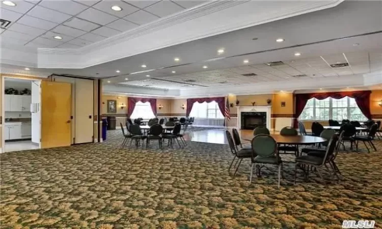 Carpeted dining space featuring a raised ceiling and crown molding