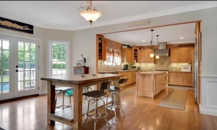 Kitchen featuring a center island, french doors, hanging light fixtures, light hardwood flooring, and tasteful backsplash