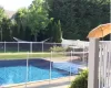 View of pool with a patio and optional child safety fence.