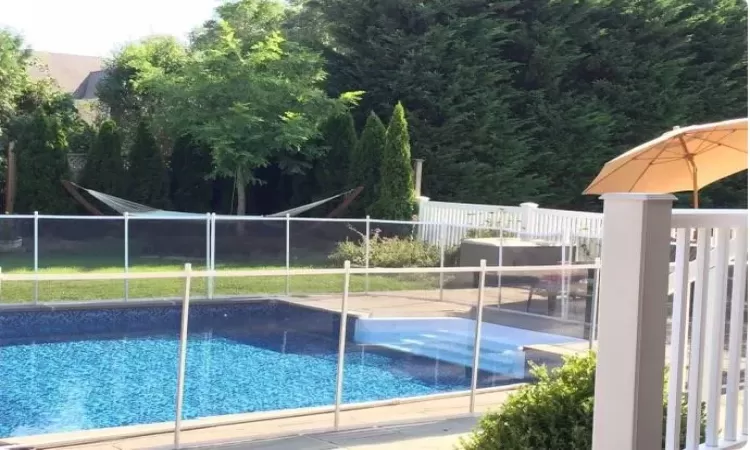 View of pool with a patio and optional child safety fence.