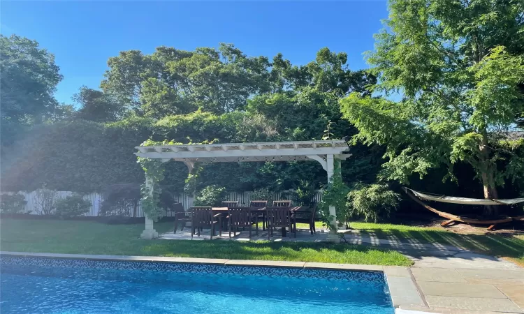 View of pool with a pergola and a lawn