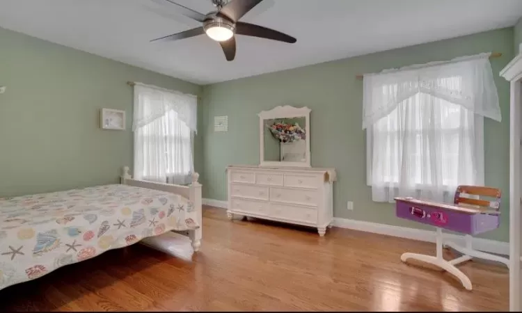 Bedroom featuring multiple windows, ceiling fan, and light wood-type flooring